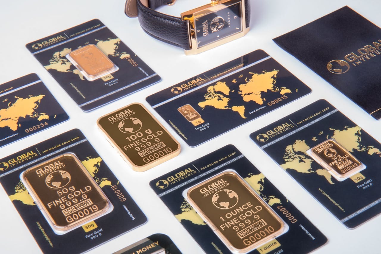 Menu High-angle shot of fine gold bars with a luxury watch and branded packaging.