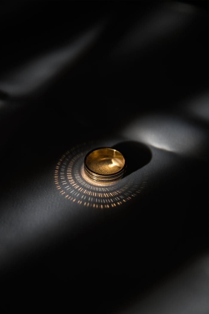 A sophisticated gold ring illuminated by artistic light patterns, creating a dramatic effect.
